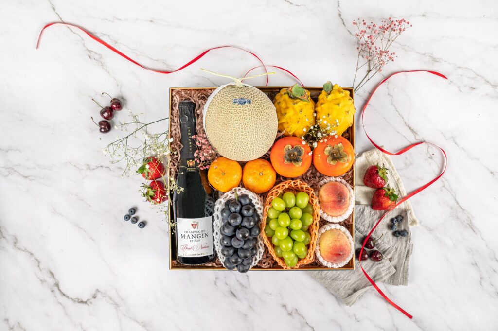 Insofresh premium fruit hamper with champagne, muskmelon, dragon fruit, persimmons, peaches, green grapes and tangerines, arranged for luxury fruit delivery in Singapore.